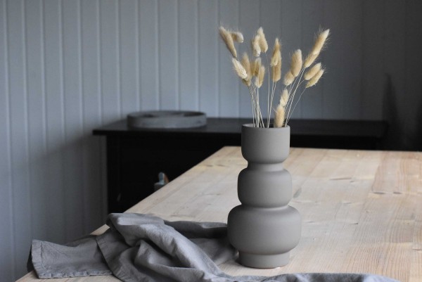Vasen in Taupe mit Trockenblumen auf einem Holztisch