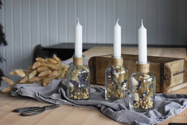Kerzengläser dekoriert auf einem Tisch mit Trockenblumen