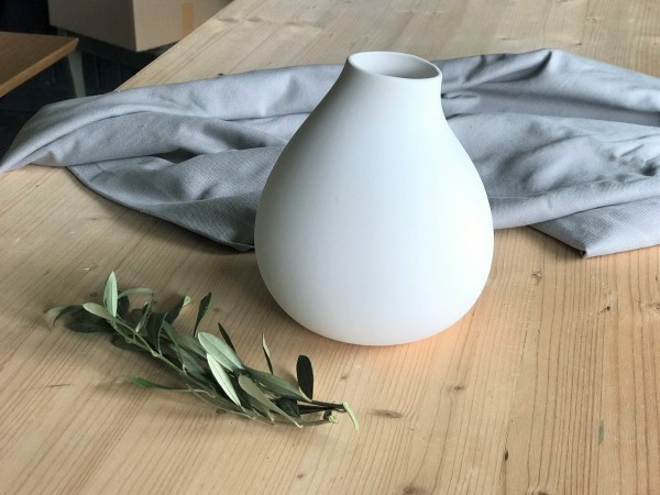 Weiße Vase von Storefactory auf einem Holztisch stehend