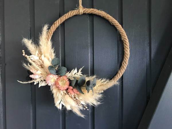 Jute-Ring mit Trockenblumen in Beige-, Braun-, Rosa-Tönen und Pampas mit Eukalyptus an einer Tür hängend